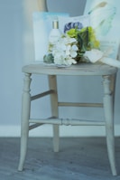 A wooden chair displaying a bouquet of white and green flowers, a bottle labeled 'Sothys', and some printed materials placed on its seat.