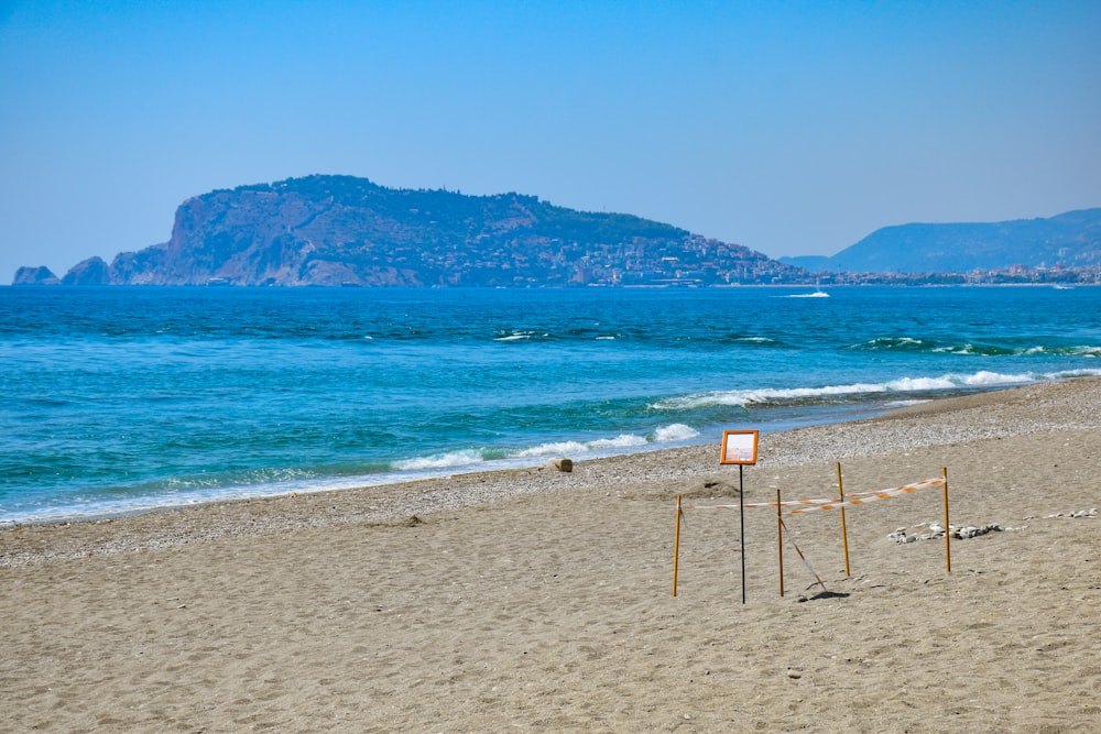 a sign on a beach with a mountain in the background