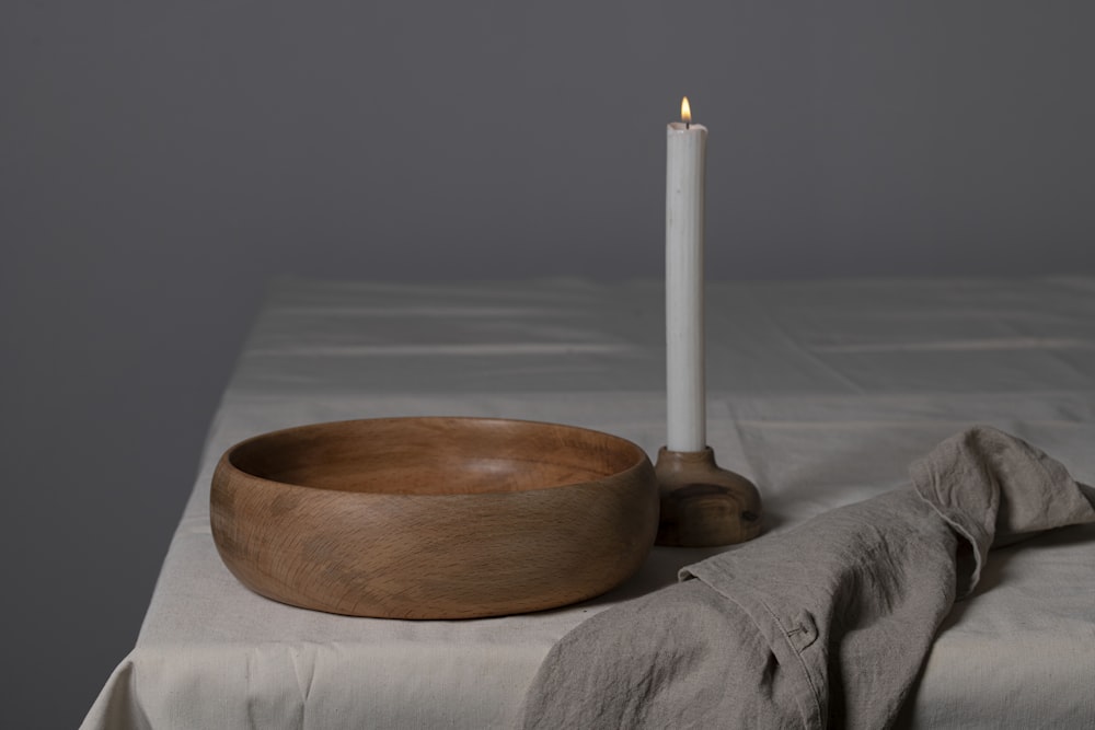 a wooden bowl and a candle on a table