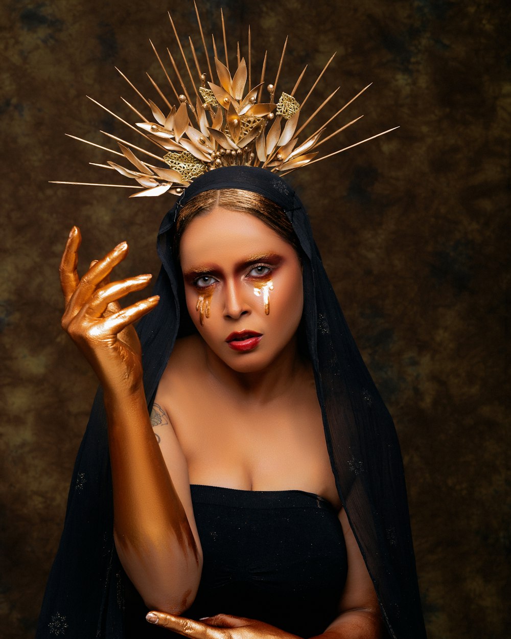 a woman in a black dress with a gold crown on her head