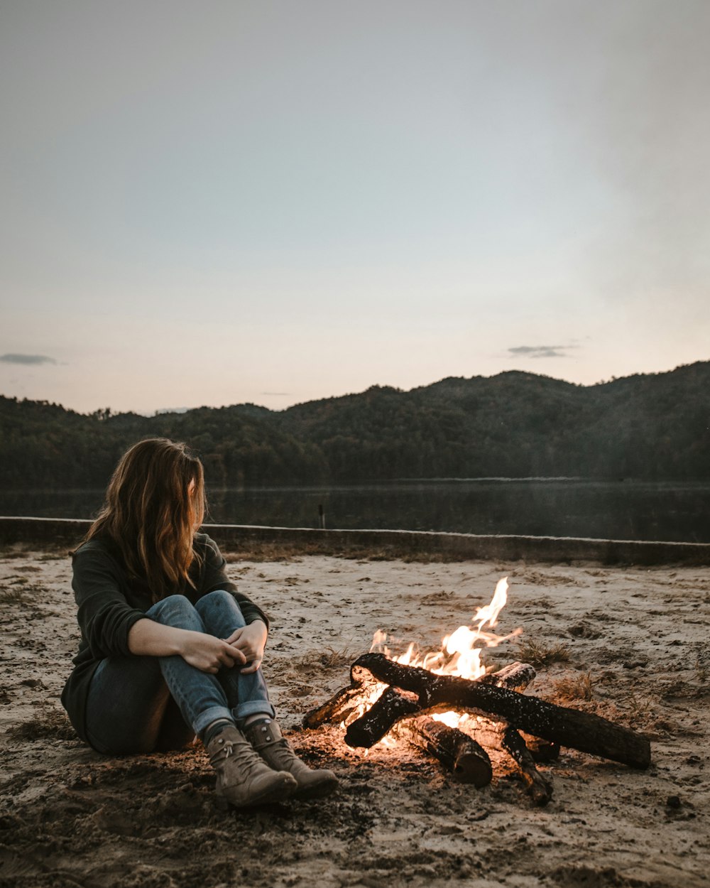 a woman sitting in front of a campfire