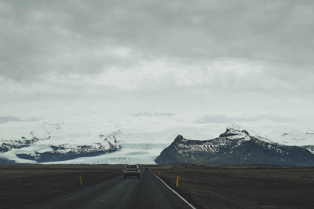Ein Auto, das eine Straße mit Bergen im Hintergrund hinunterfährt