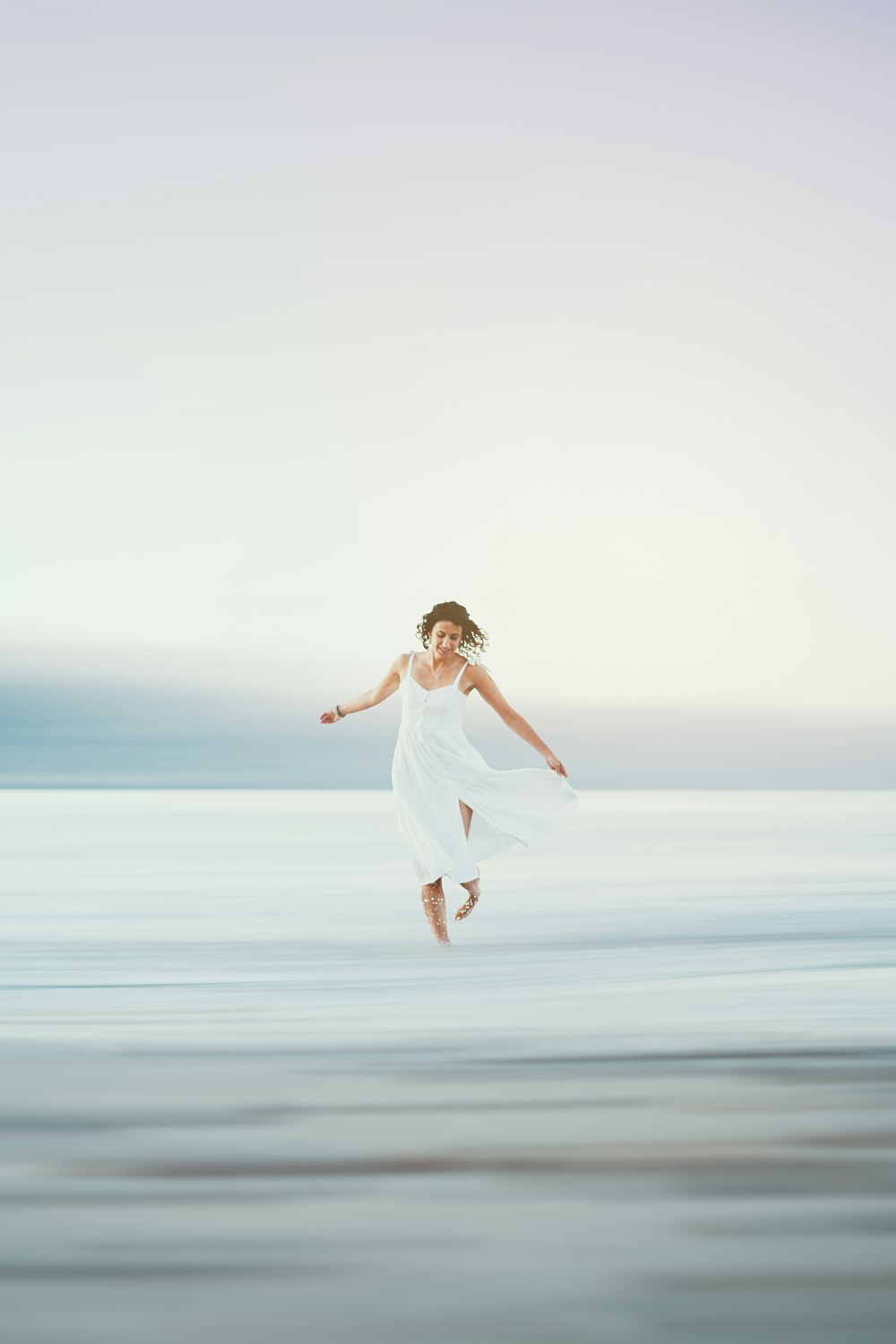 uma mulher em um vestido branco pulando no ar