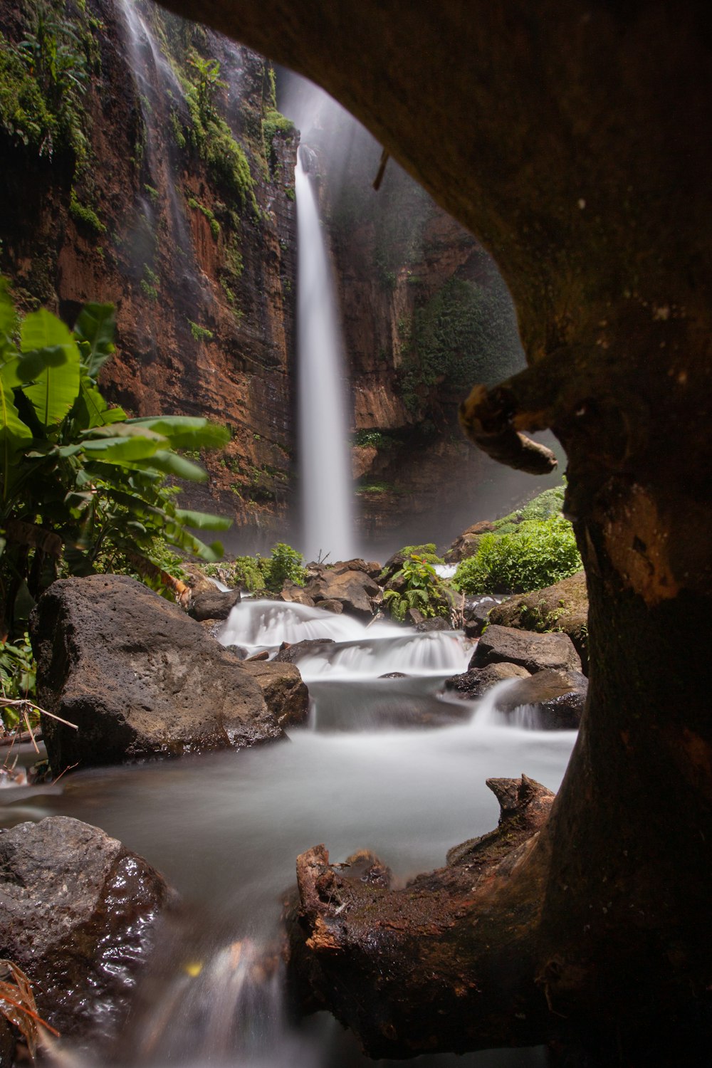 a waterfall is seen through a hole in a rock