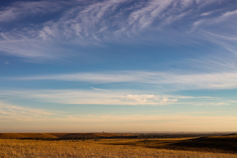 a large open field with a few clouds in the sky