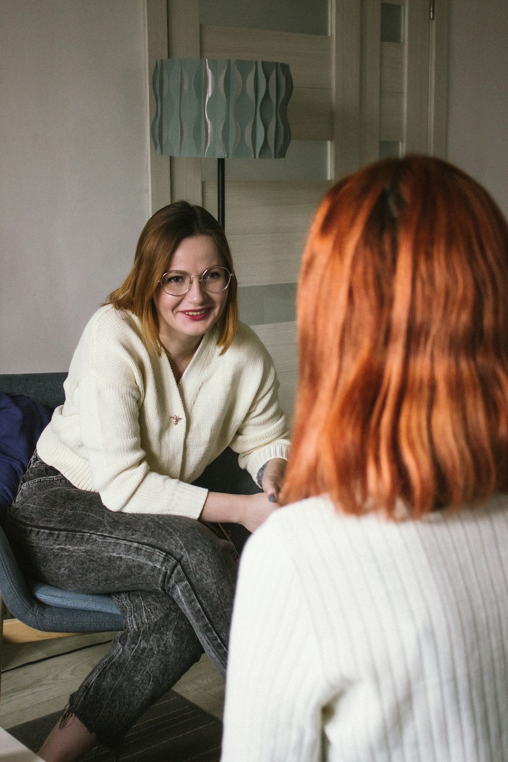 a woman sitting on a couch talking to another woman