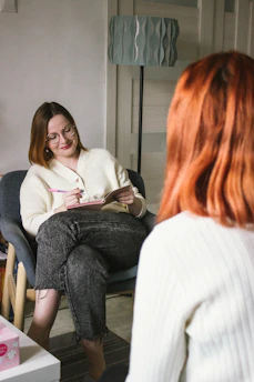 a woman sitting in a chair looking at a book