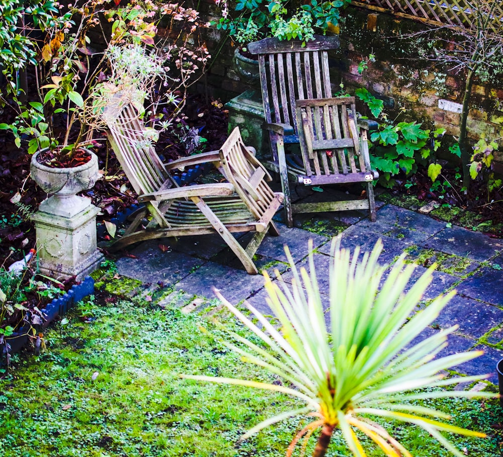 a couple of wooden chairs sitting on top of a lush green field