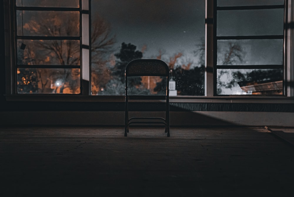 a chair sitting in front of a window at night