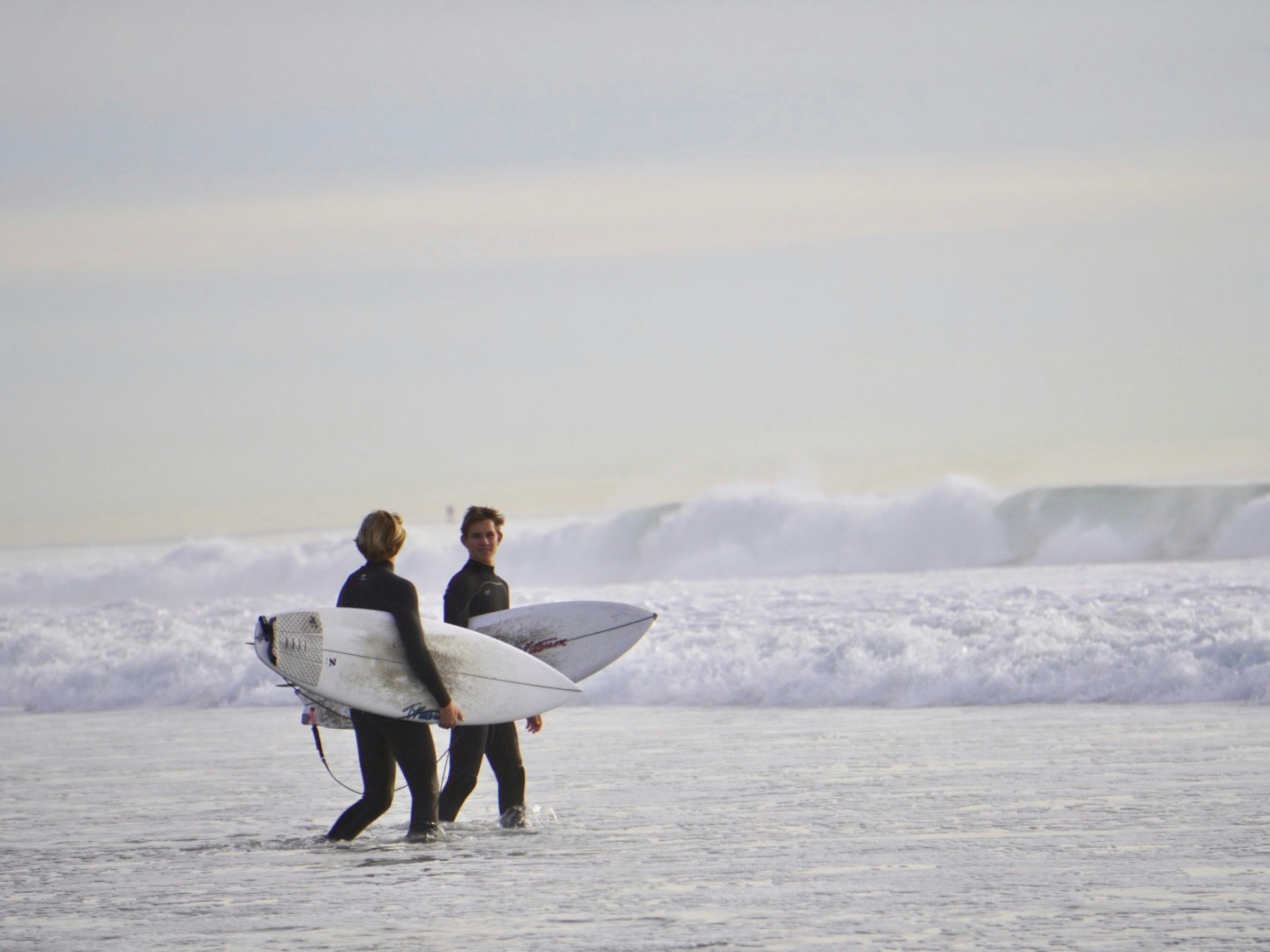 a couple of people that are standing in the water with surfboards