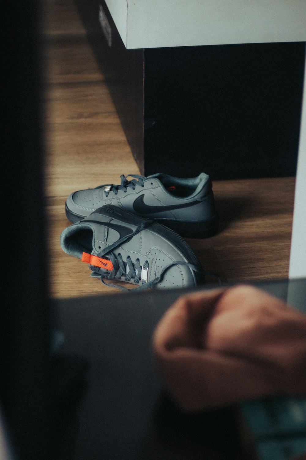 a pair of grey sneakers sitting on top of a wooden floor