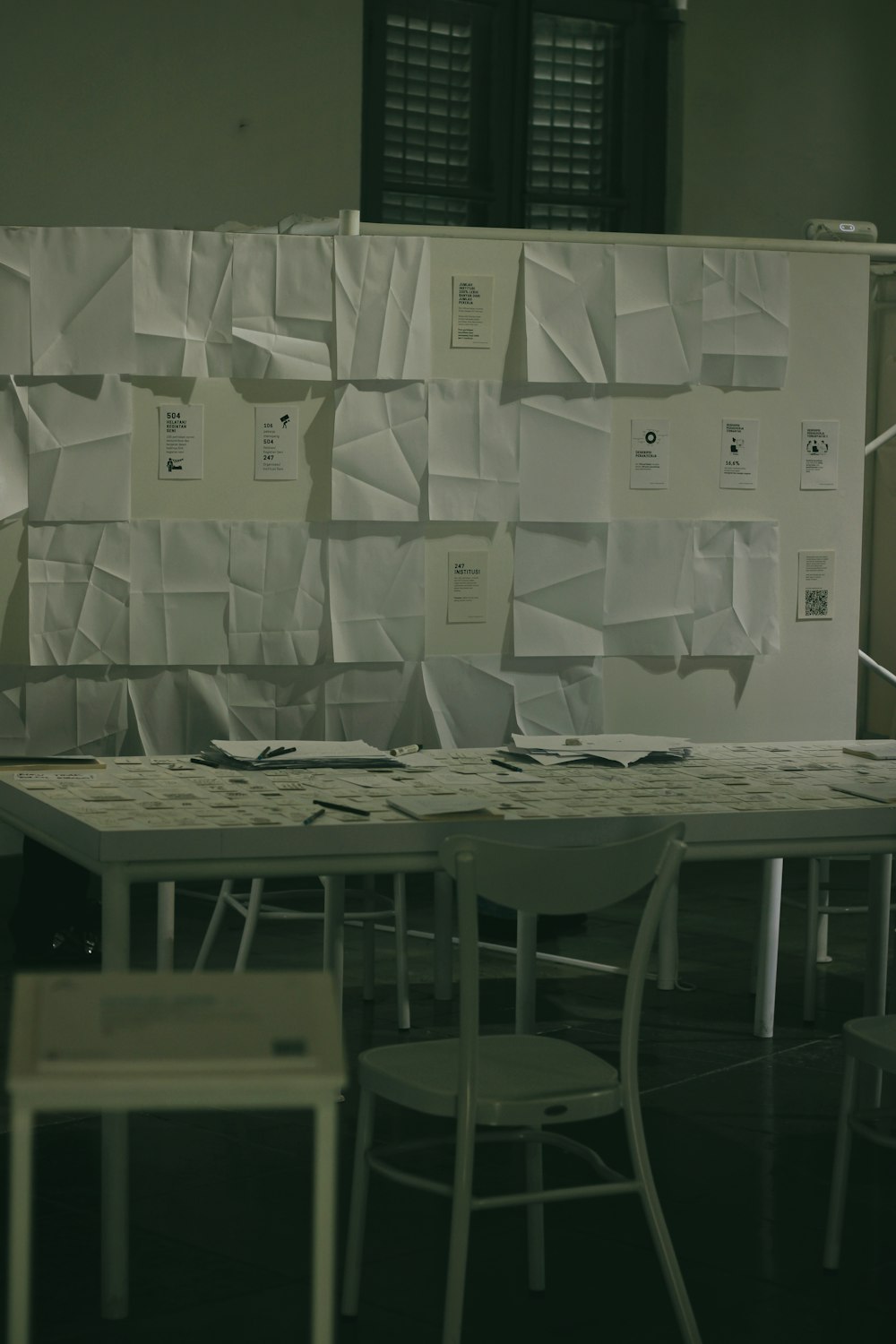 a room with several tables and chairs covered in papers