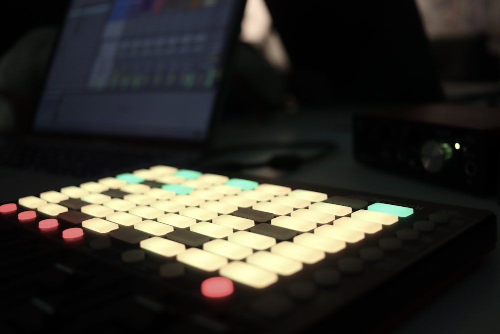 a close up of a keyboard with a laptop in the background