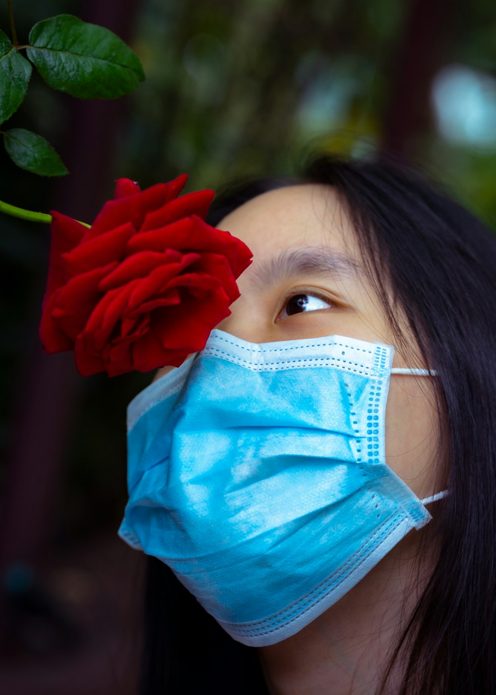 a woman wearing a face mask and a red rose