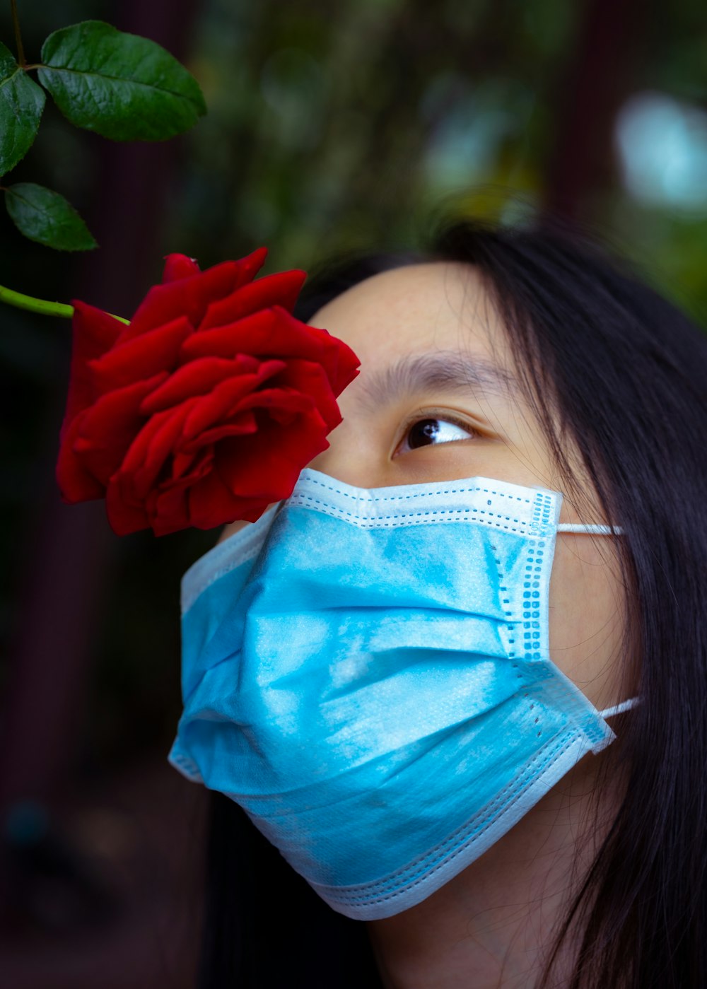 Eine Frau mit Gesichtsmaske und roter Rose