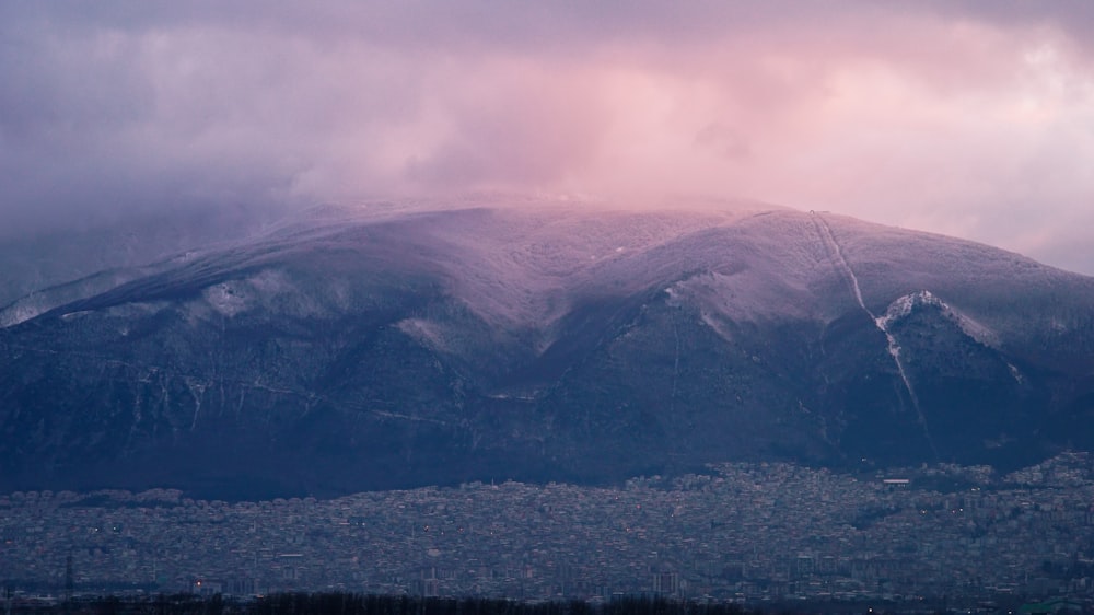 a mountain covered in snow under a cloudy sky