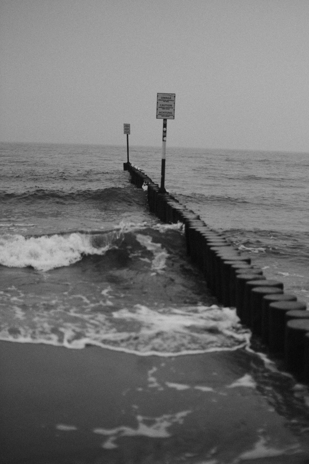 a black and white photo of a pier in the ocean