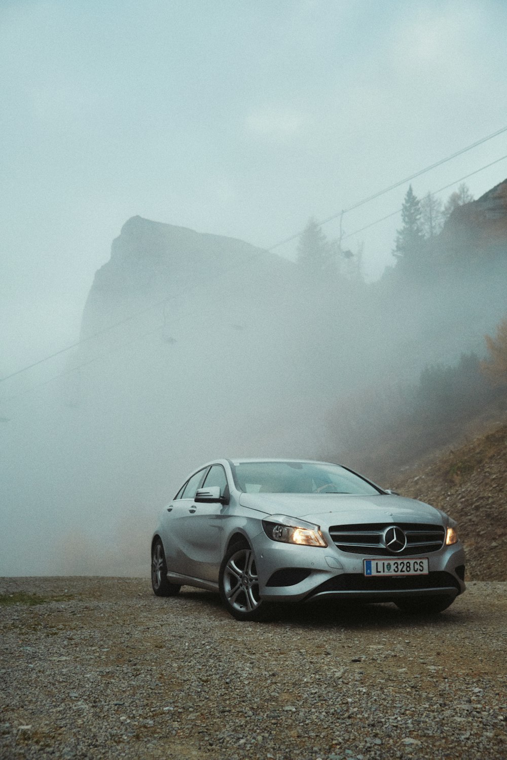 a silver car driving down a dirt road