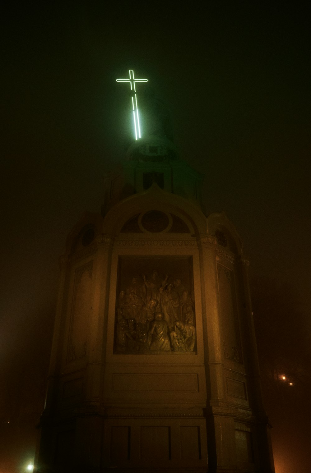 a cross on top of a building lit up at night