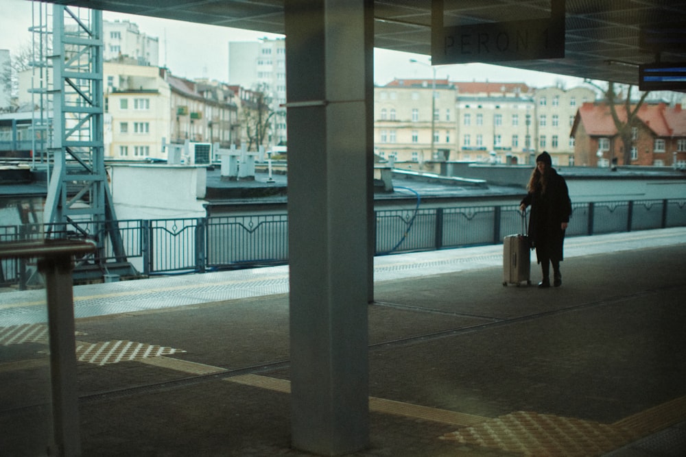 a woman with a suitcase waiting for a train