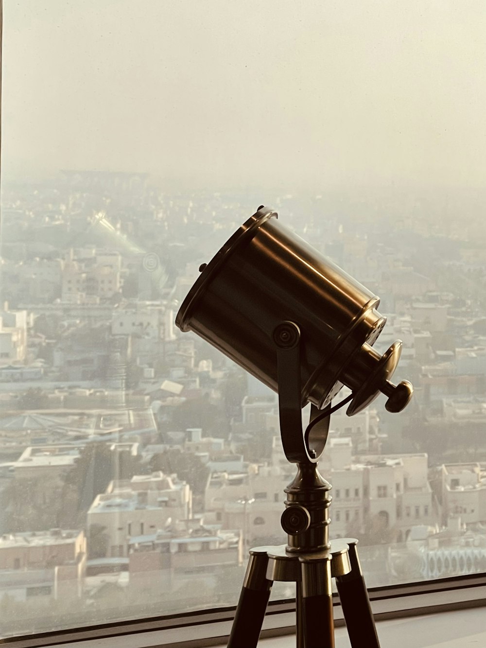 a telescope sitting on top of a tripod in front of a window