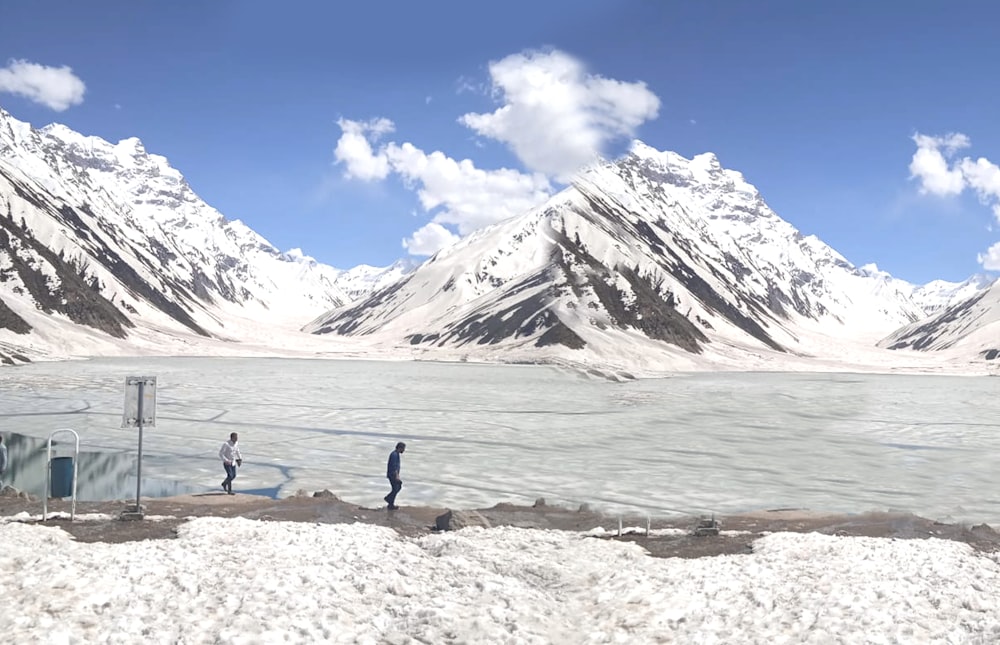 a couple of people walking across a snow covered field