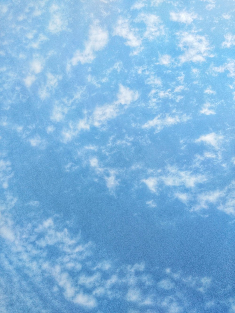 an airplane flying through a blue cloudy sky