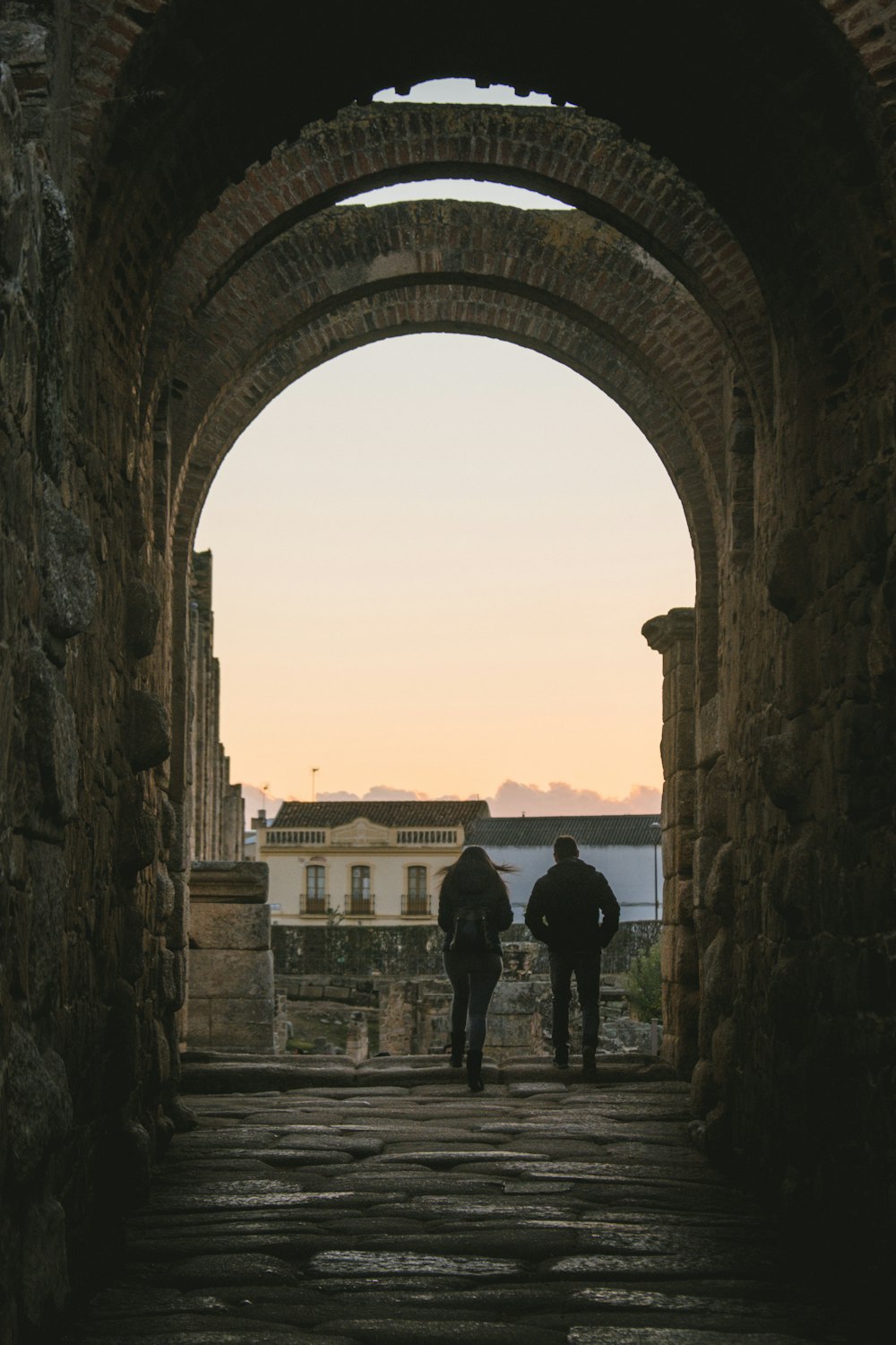 a couple of people that are walking under an arch