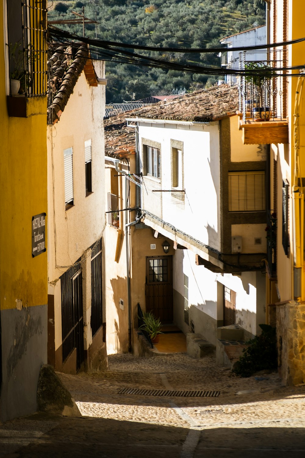 a narrow alley way with buildings and a mountain in the background