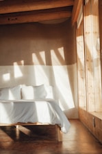 Cozy rustic bedroom with warm earth tones and natural light streaming through a window overlooking the countryside.