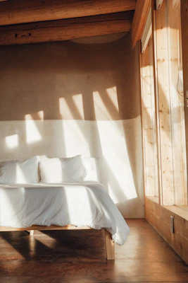 A cozy bedroom featuring a plush mattress and a sturdy wooden bed frame bathed in soft natural light.