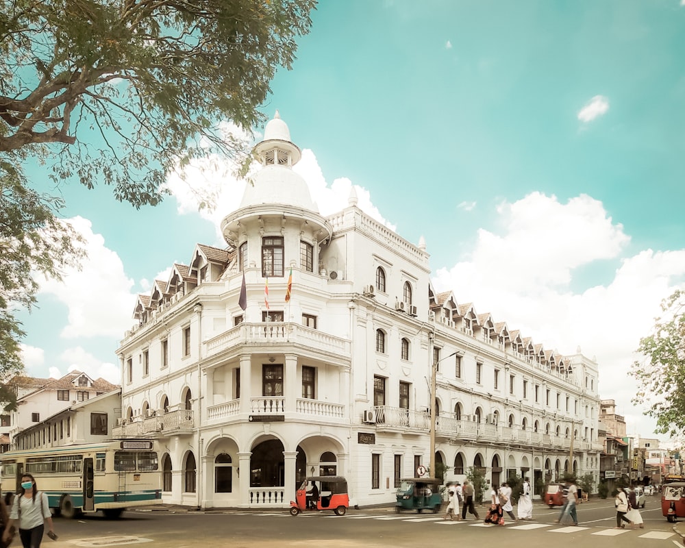 Un gran edificio blanco con un autobús estacionado frente a él