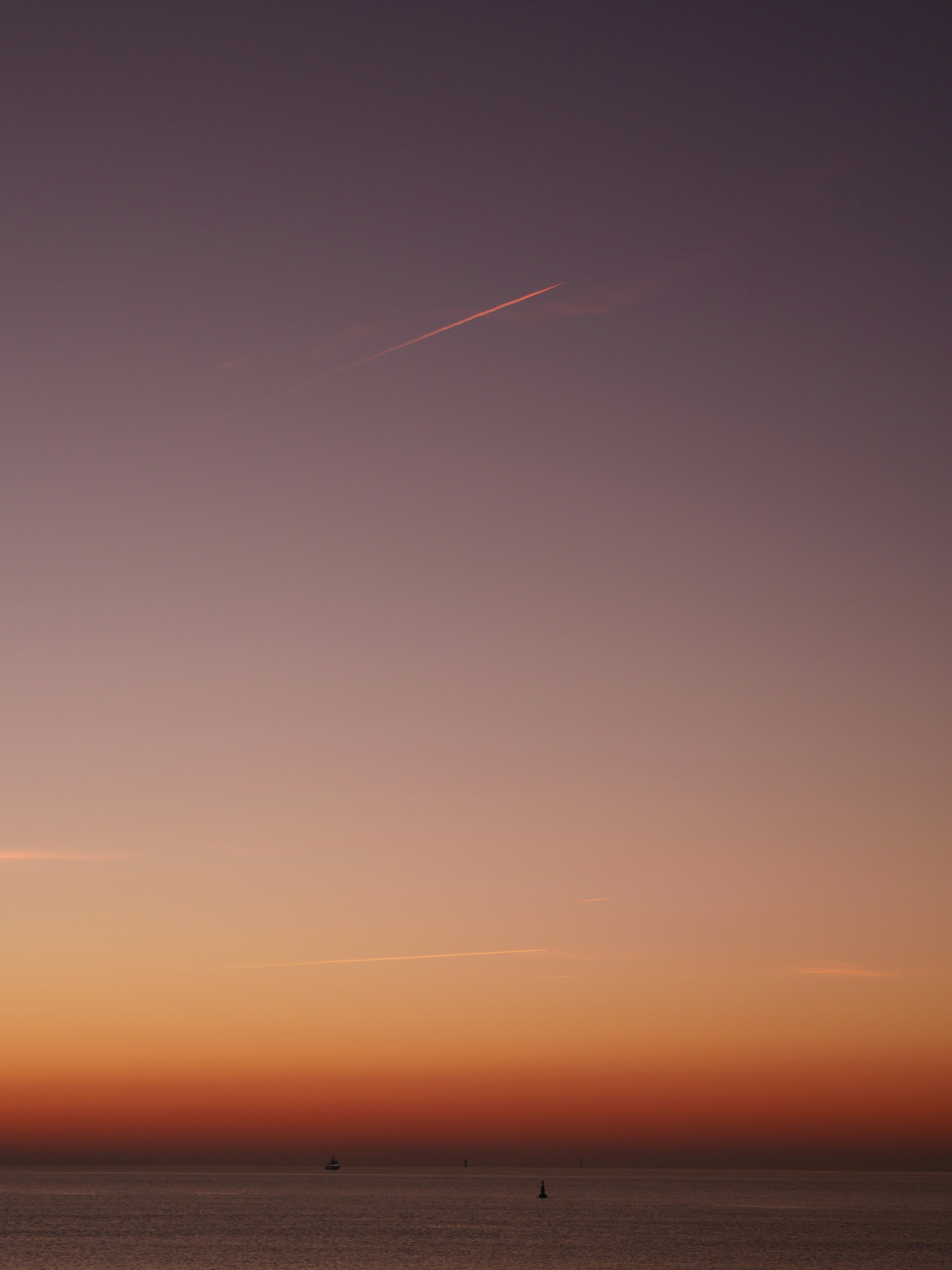 a plane flying over a body of water at sunset