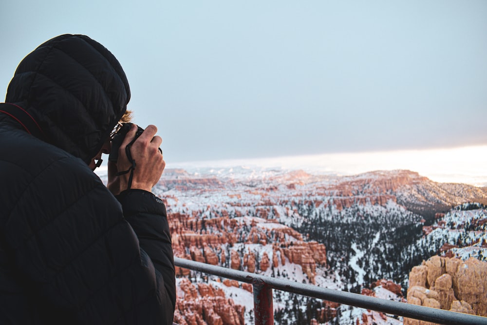 a man in a black jacket looking out over a snowy landscape