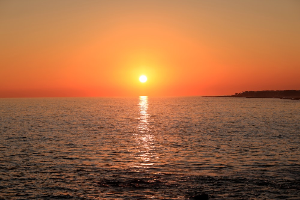 a large body of water with a sunset in the background