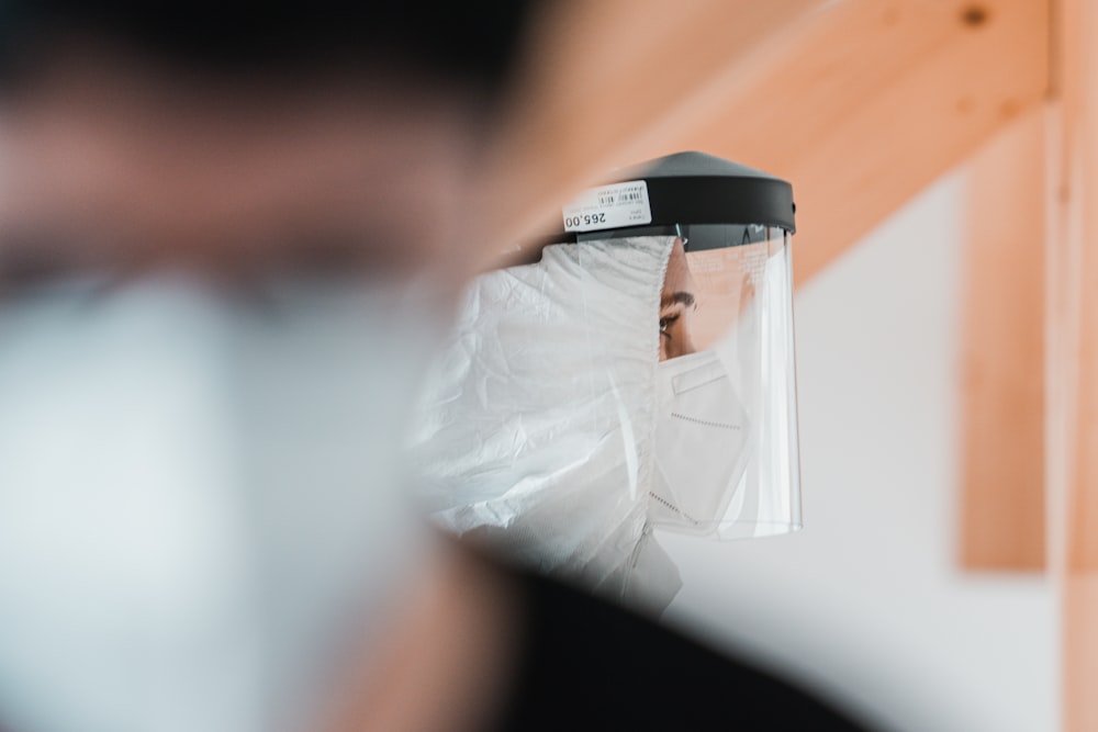 a person wearing a face mask and covering their face with a plastic bag