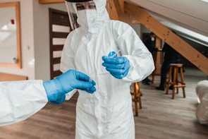 a person in a white suit and blue gloves
