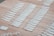 Numerous white rapid test kits are arranged in neat rows on a wooden surface. Each kit appears to have numbers or labels marked on them, likely for identification purposes.