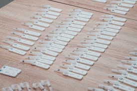 Numerous white rapid test kits are arranged in neat rows on a wooden surface. Each kit appears to have numbers or labels marked on them, likely for identification purposes.