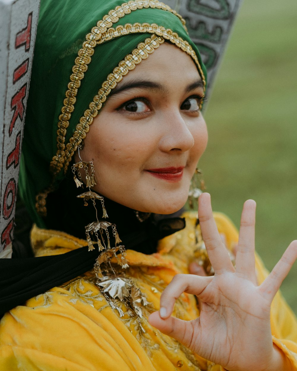 a woman in a green headdress making a peace sign