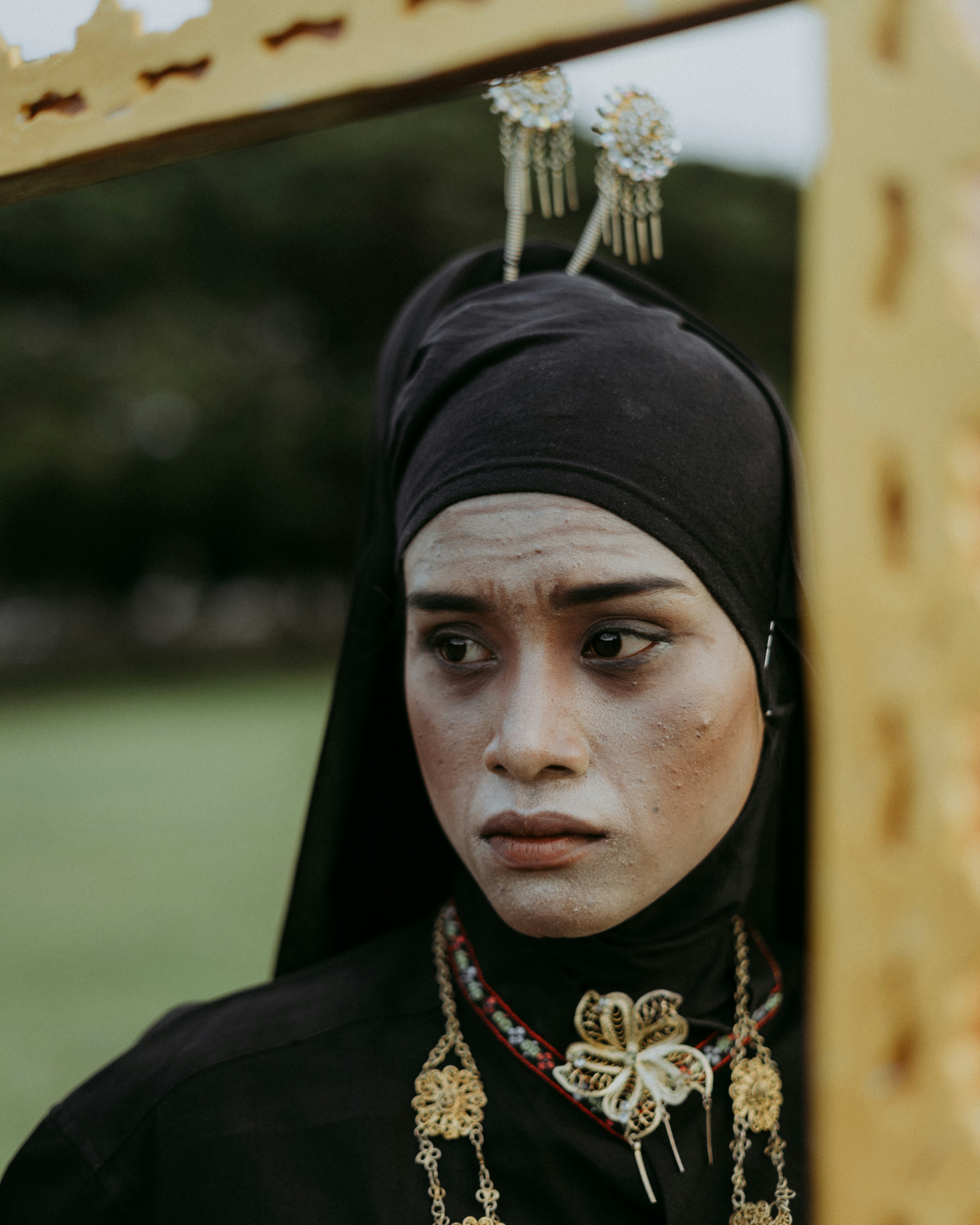 seorang wanita mengenakan hiasan kepala hitam dan perhiasan