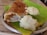 A crispy brown dosa placed on a banana leaf with a serving of white chutney and mashed potatoes on a metal plate.