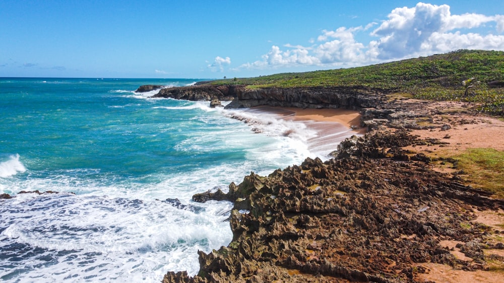 a sandy beach next to the ocean under a blue sky