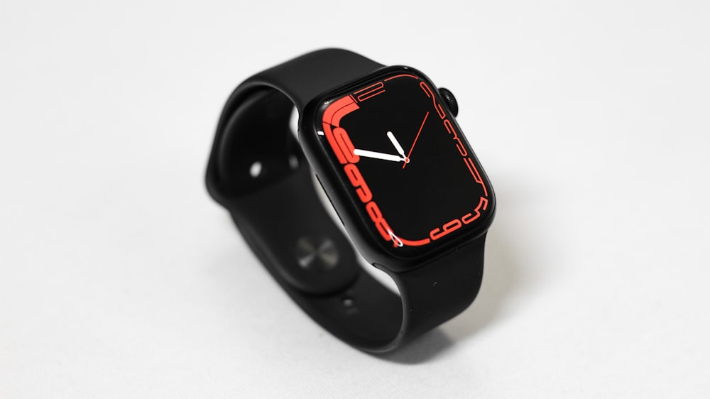 a black watch with a red face on a white surface