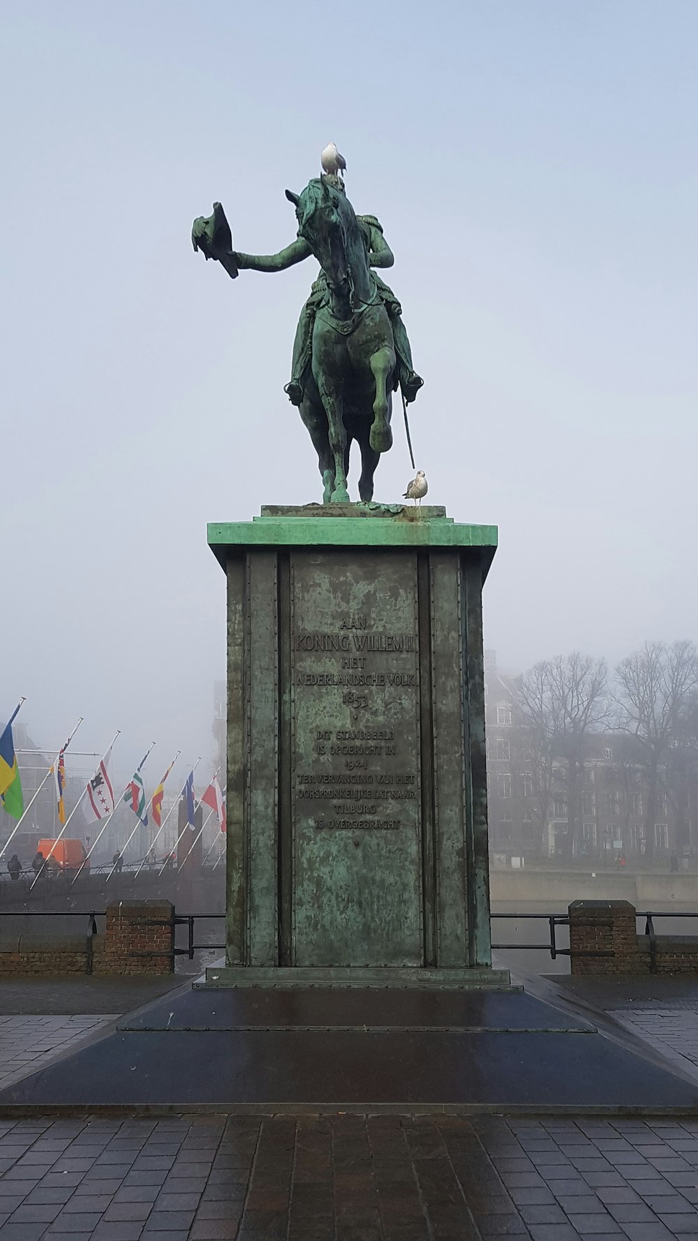 a statue of a man on a horse with flags in the background