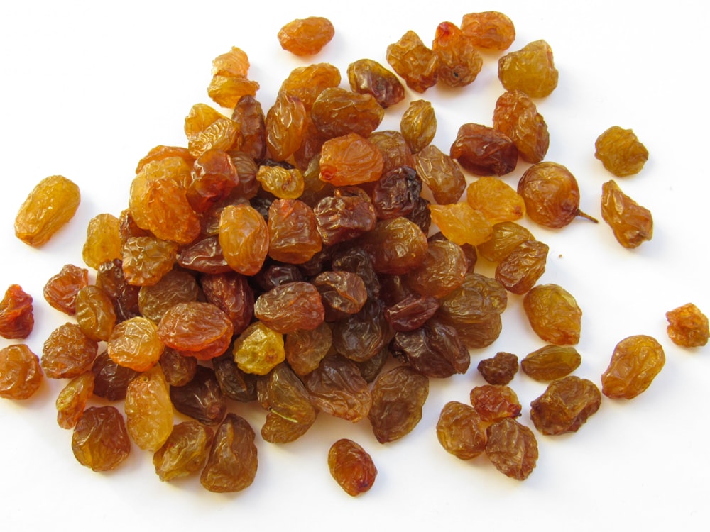 a pile of raisins on a white surface