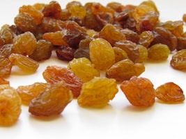 Clusters of sun-kissed raisins glistening on a simple white plate with a backdrop of earthy tones.
