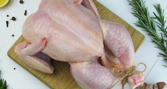 a raw chicken on a cutting board next to a slice of lemon