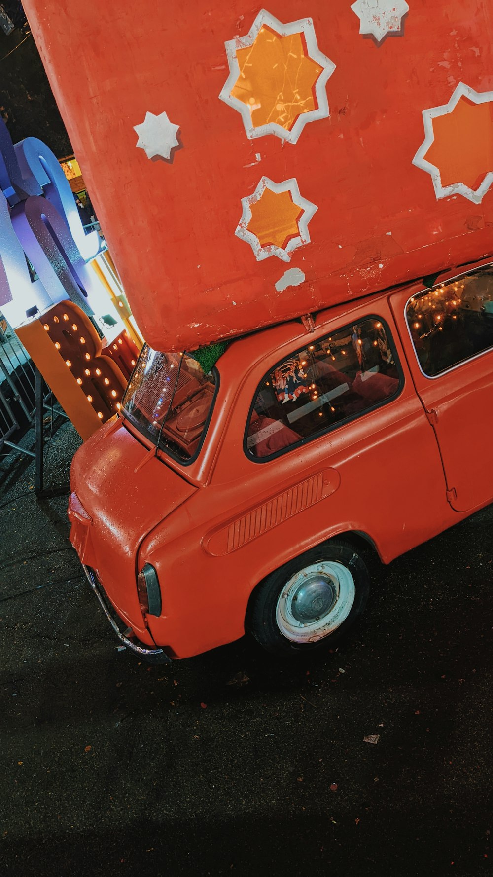 an orange car with a large piece of luggage on top of it