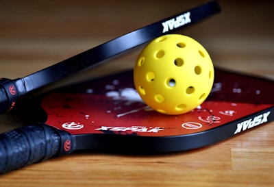 a yellow tennis ball sitting on top of a racket